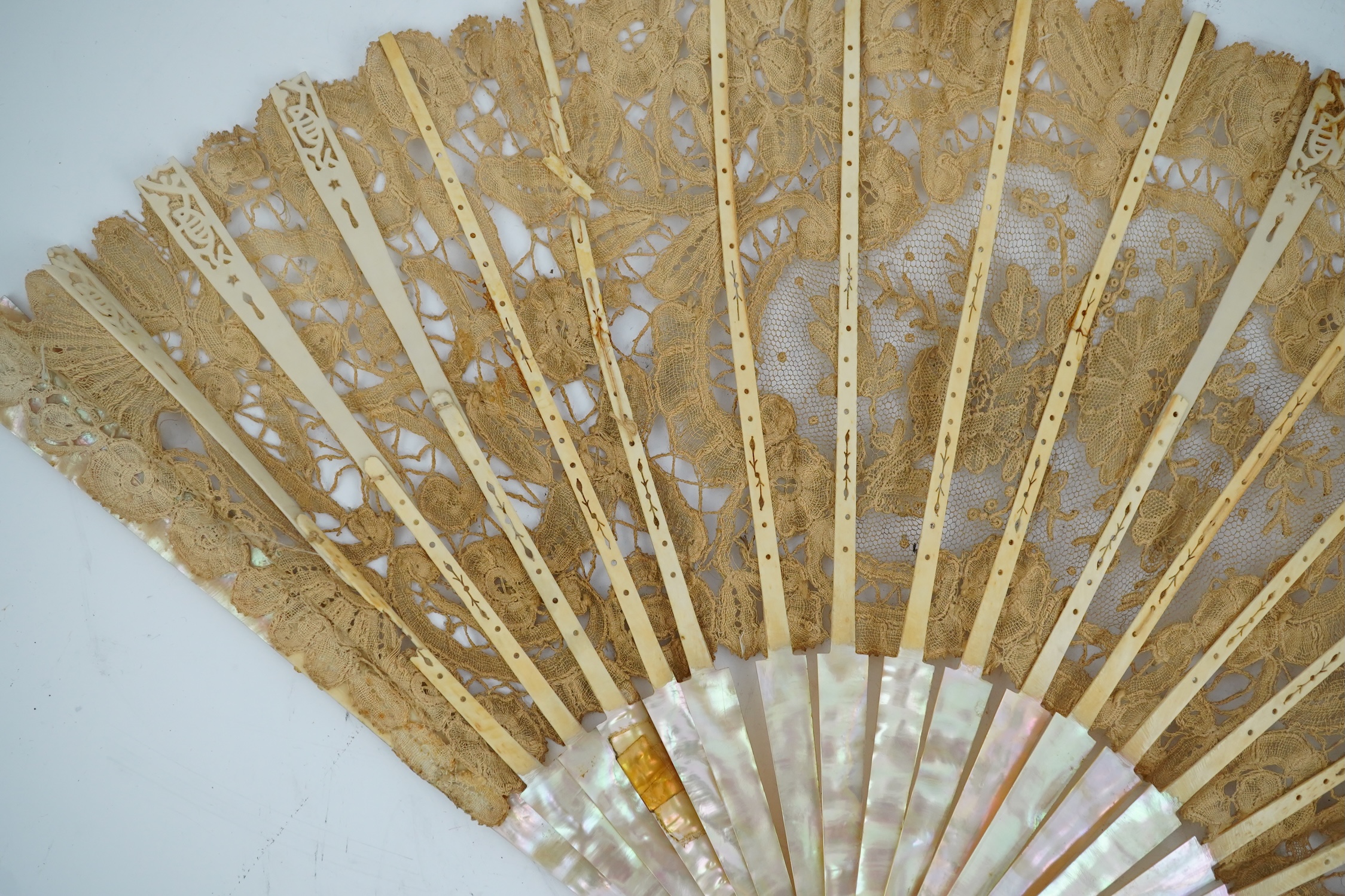 Three novelty fans with a mixed Brussels lace fan and black lace fan, a small language of love in flowers fan, a paper windmill advertising French Café fan, a carved cream Bakelite fan, a black and gilt, lace and sequin